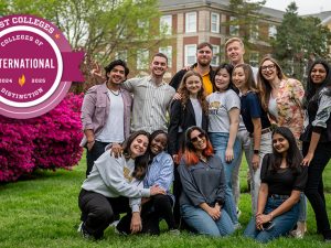 A group of smiling students outside on the lawn, with a purple badge reading: “Best Colleges - Colleges of Distinction - International, 2024–2025”