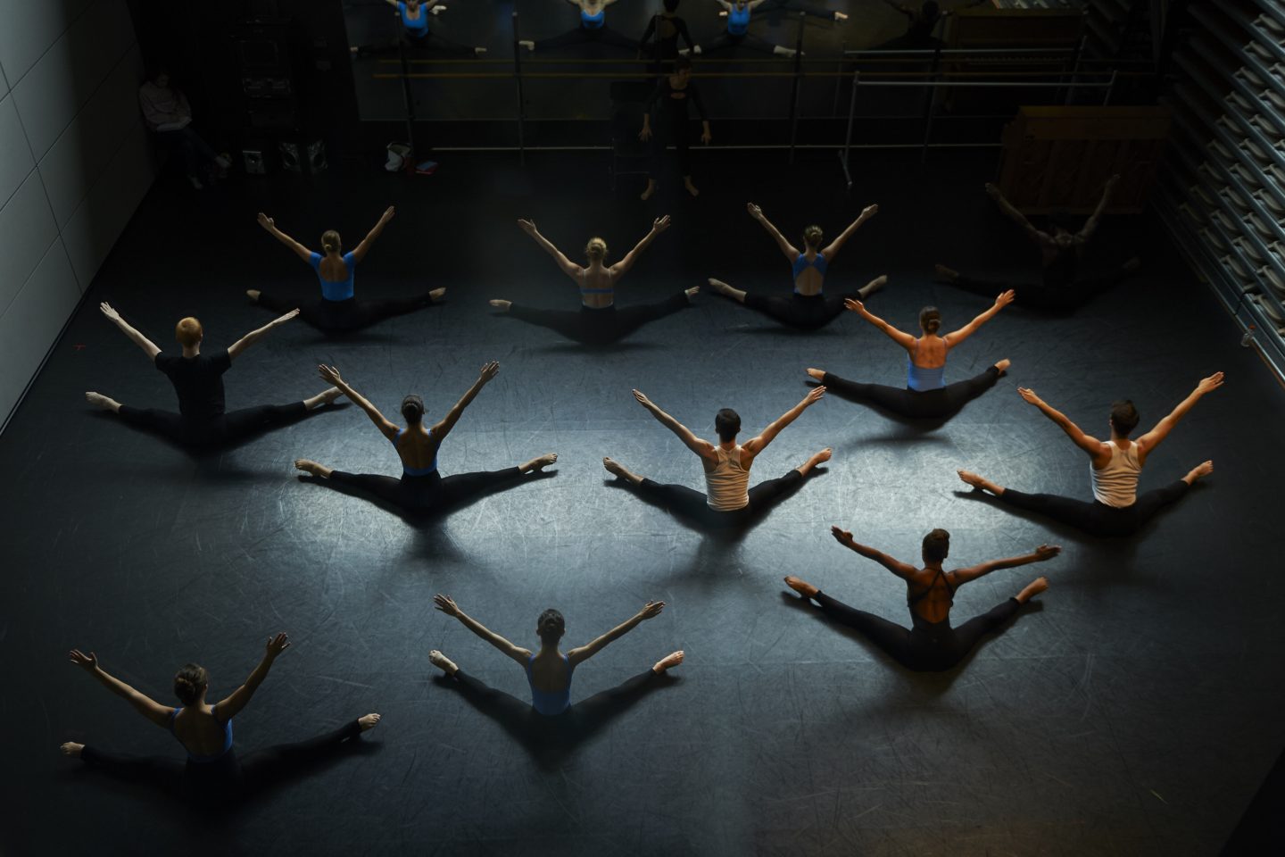 Eleven students rehearse modern dance on a darkened stage.