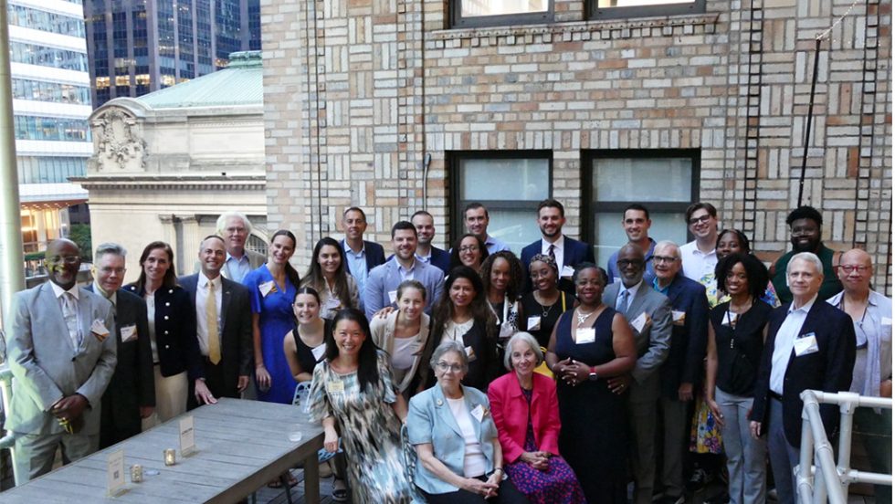 Group photo of men and women in a outside on a rooftop.