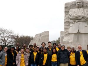 Two lines of people standing in front of a statue of a Black man