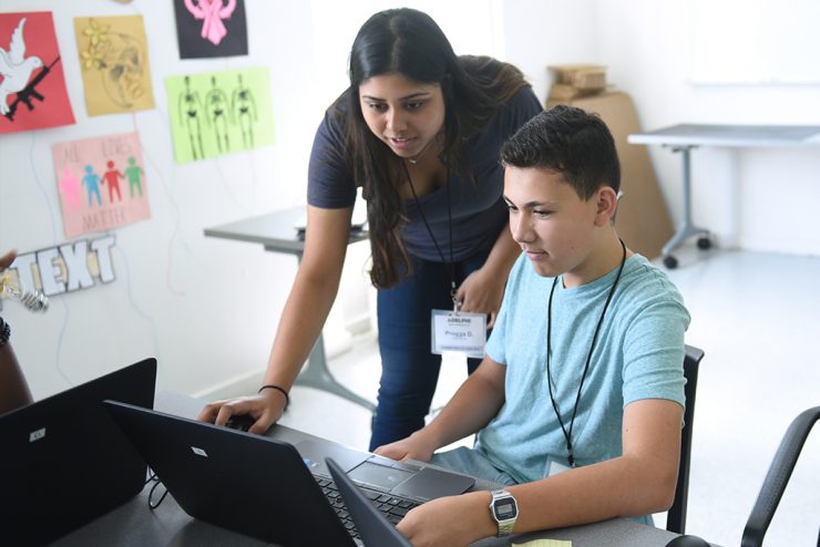 A supervisor teaching a student how to do a task on the computer.