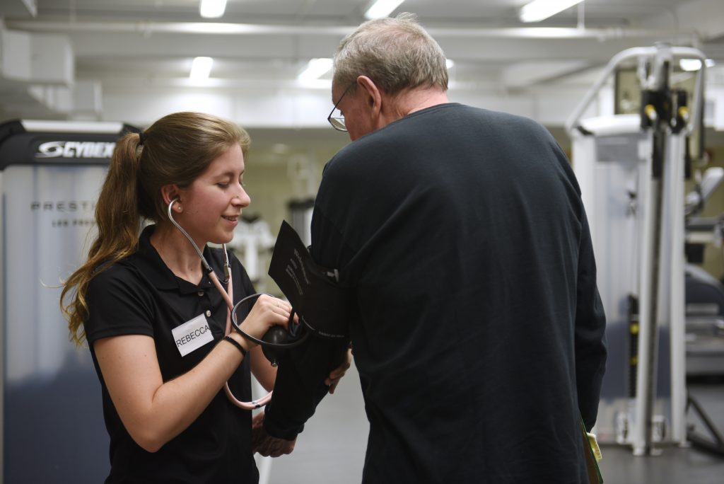 Senior citizen getting their blood pressure taken during Adult Fitness, by a volunteer.