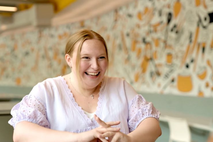 Sarah Carbain laughing with friends in the Ruth S Harley University Center dining hall at Adelphi University.