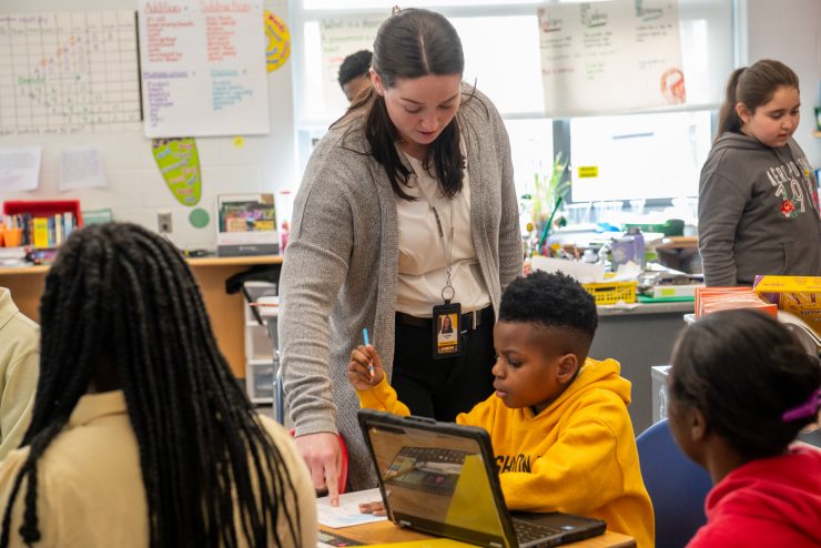 Adelphi University student teacher in the classroom working with elementary kids on Chromebooks.