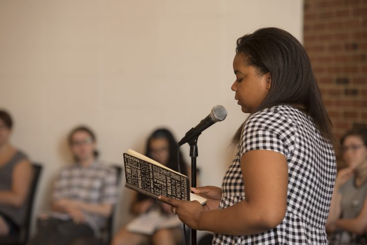 A teen girl reads her poem at a microphone during the Adelphi University Alice Hoffman Young Writers Retreat