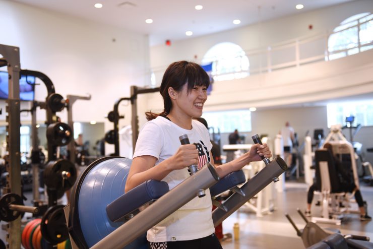 Smiling Adelphi University student using gym equipment.