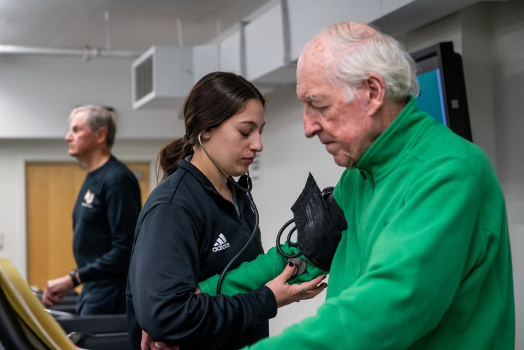 Senior citizen getting their blood pressure taken during Adult Fitness, by a volunteer.