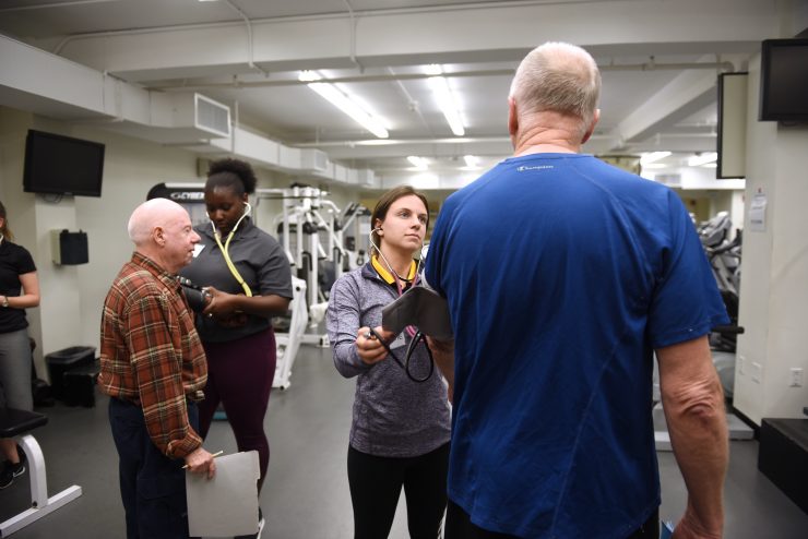 Senior citizens working out on exercise equipment and getting blod pressure checked at Adelphi University.