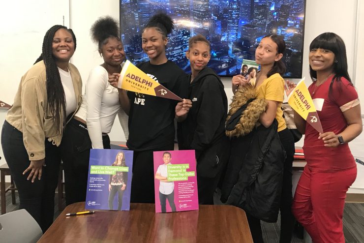 Jennifer Mathurin (far left) and Taylur Hayes (far right) visit with students from Sewanhaka High School.