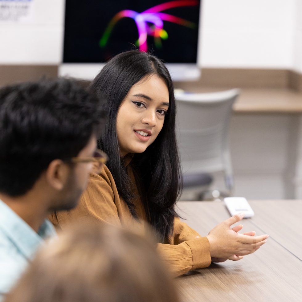 A CSD student at Adelphi University working in a laboratory on research and in a discussion.