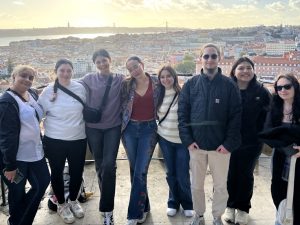 Eight Adelphi students pose above a scenic view of Lisbon, Portugal.