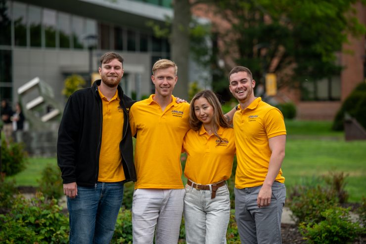 International Services staff wearing matching gold Adelphi polo shirts.