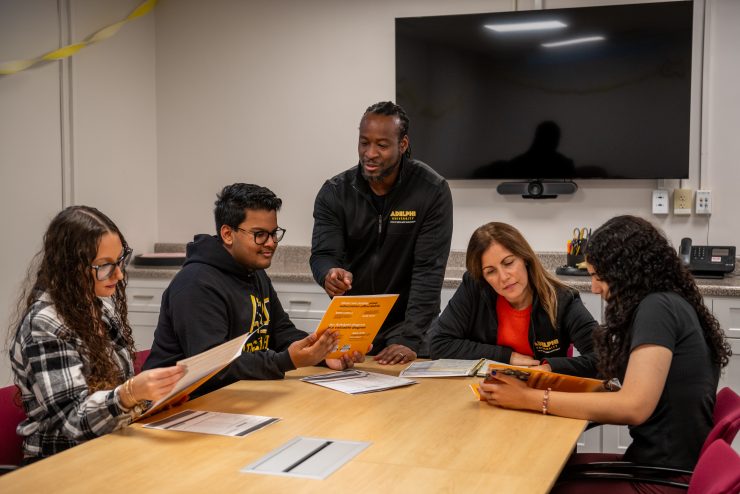 A diverse group of employees at the One Stop Student Services Center work collaboratively at Adelphi