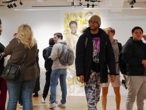 Students mingle at the Ruth S. Harley University Center Gallery, with a large sketch of James Baldwin in the background.