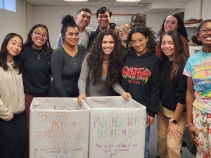 A group of students gather around food collection boxes.