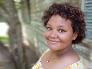 Headshot of a young woman with short Afro smiling at camera