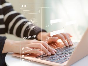 A close-up of a students hands on a laptop's keyboard, overlaid with an image of an AI chatbot search screen.