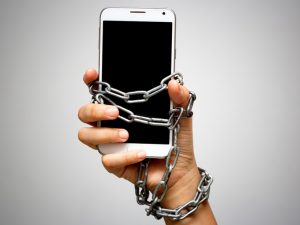 Image of a smartphone chained to someone's hand.