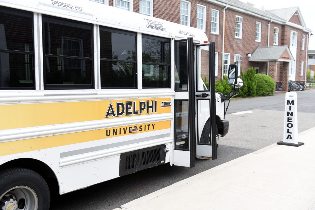 An Adelphi shuttle bus with open doors going to Mineola.