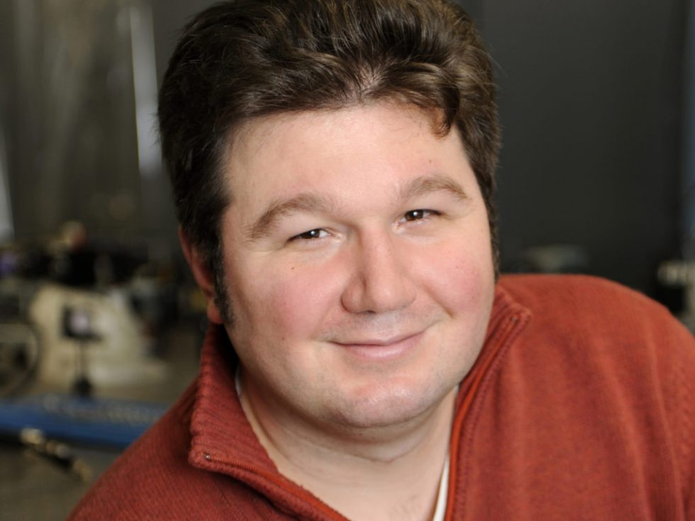 Man with red shirt smiling at camera. 