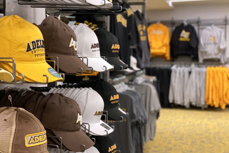 Adelphi University bookstore showing baseball hats with the University logo.