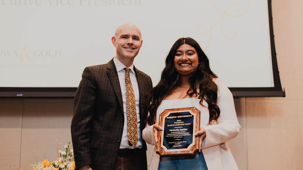 Man stands next to young woman holding up a plaque