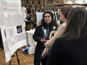  A woman in front of a poster talking with two other women