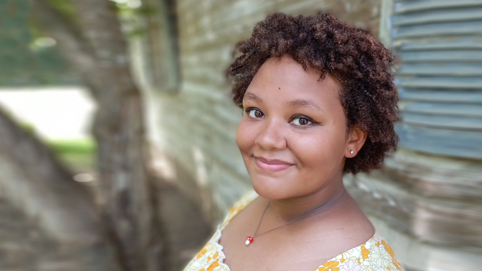 Headshot of a young woman with short Afro smiling at camera