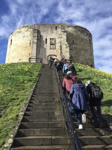 Students walking up stone steps to a building on top of a hill.