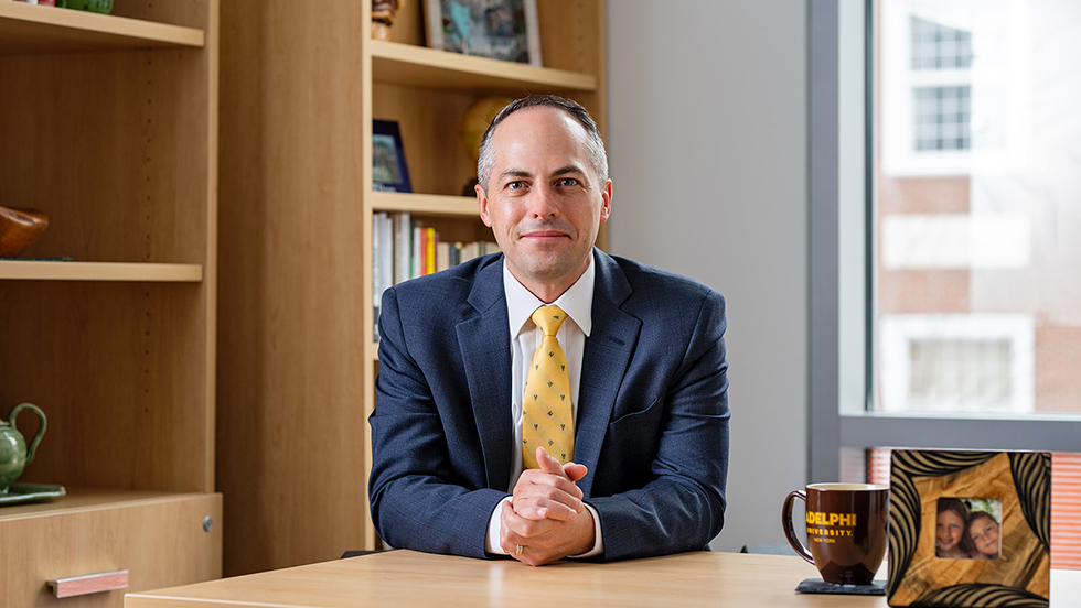 Dr. Kline, dressed in business attire, at his desk, looking at the camera. 