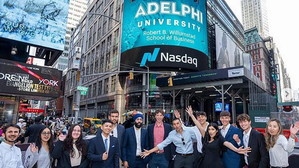 Thirteen students stand in front of the Nasdaq stock exchange building in Manhattan.