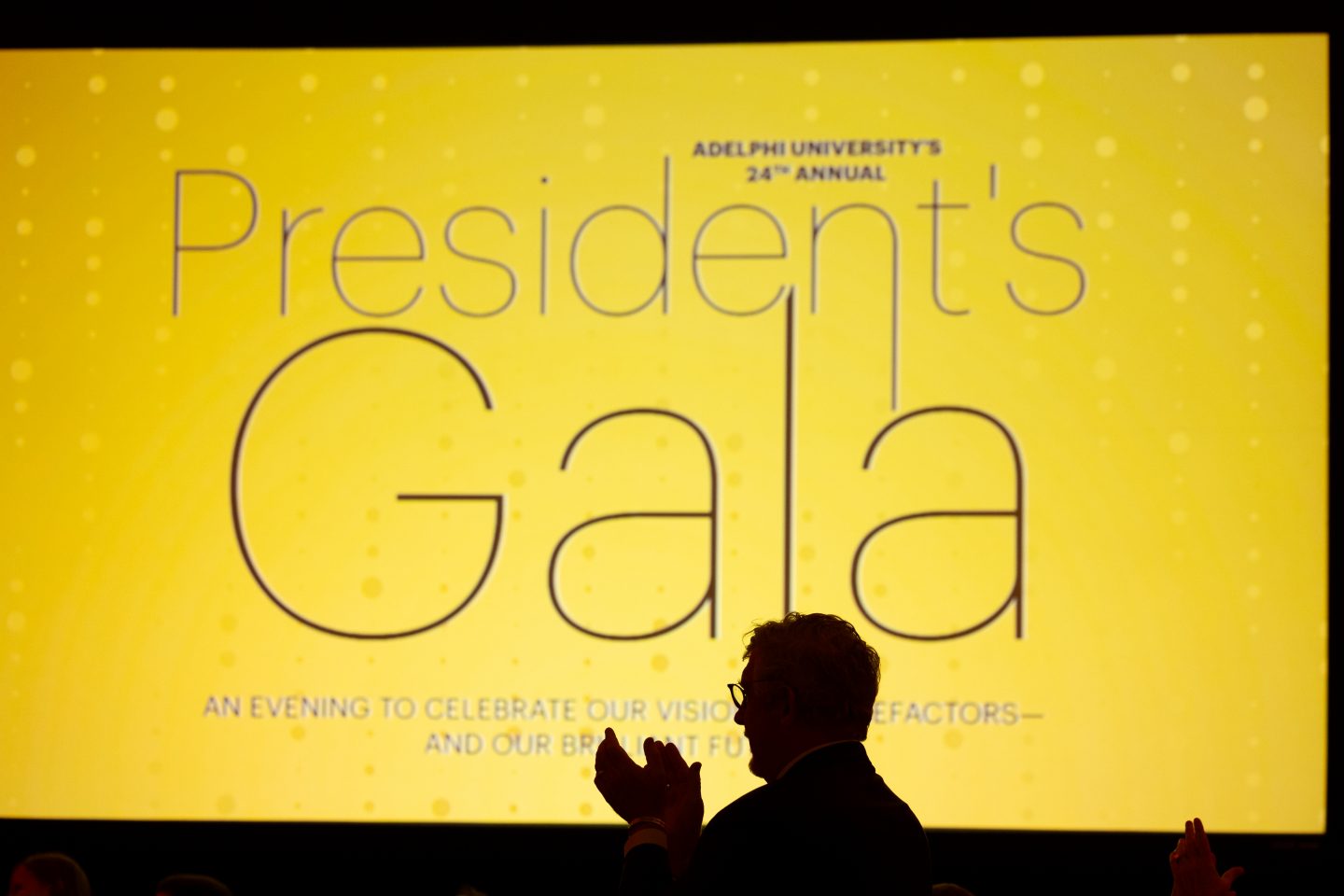 President's Gala logo projected on a screen with a silhouetted figure in the foreground.