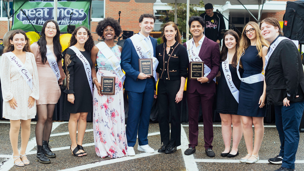 Group of Adelphi students with President of Adelphi posing in front of building.