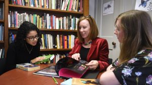 Professor Geddes works with a student at a table in her office.