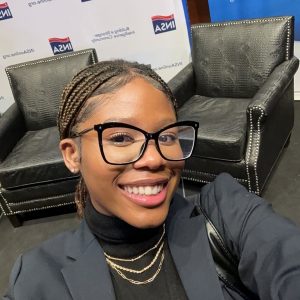  A selfie of a woman in glasses in front of two chairs.