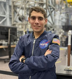  A man, arms crossed, wearing a blue NASA jacket.