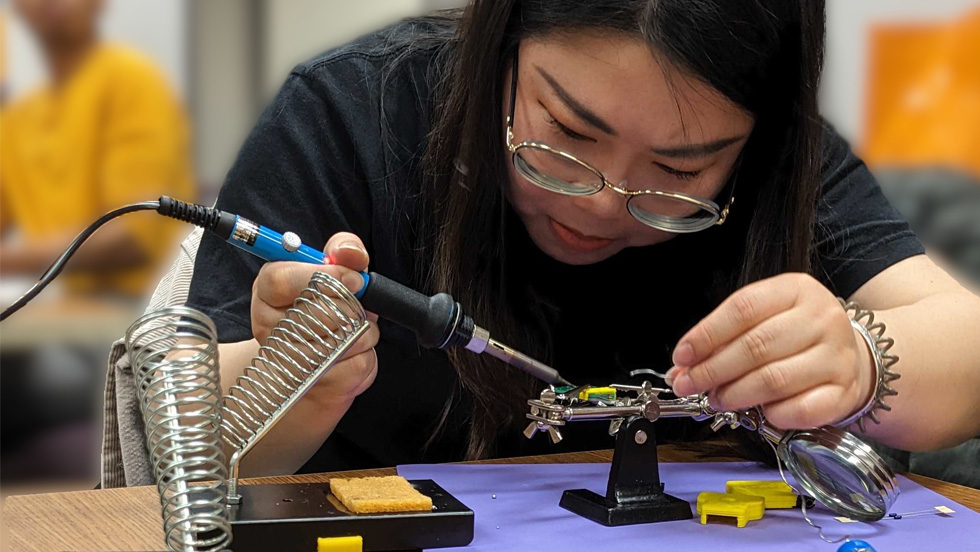 A young student uses a tool to work on a project.