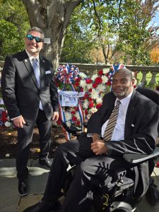 Two men in front of flower memorials