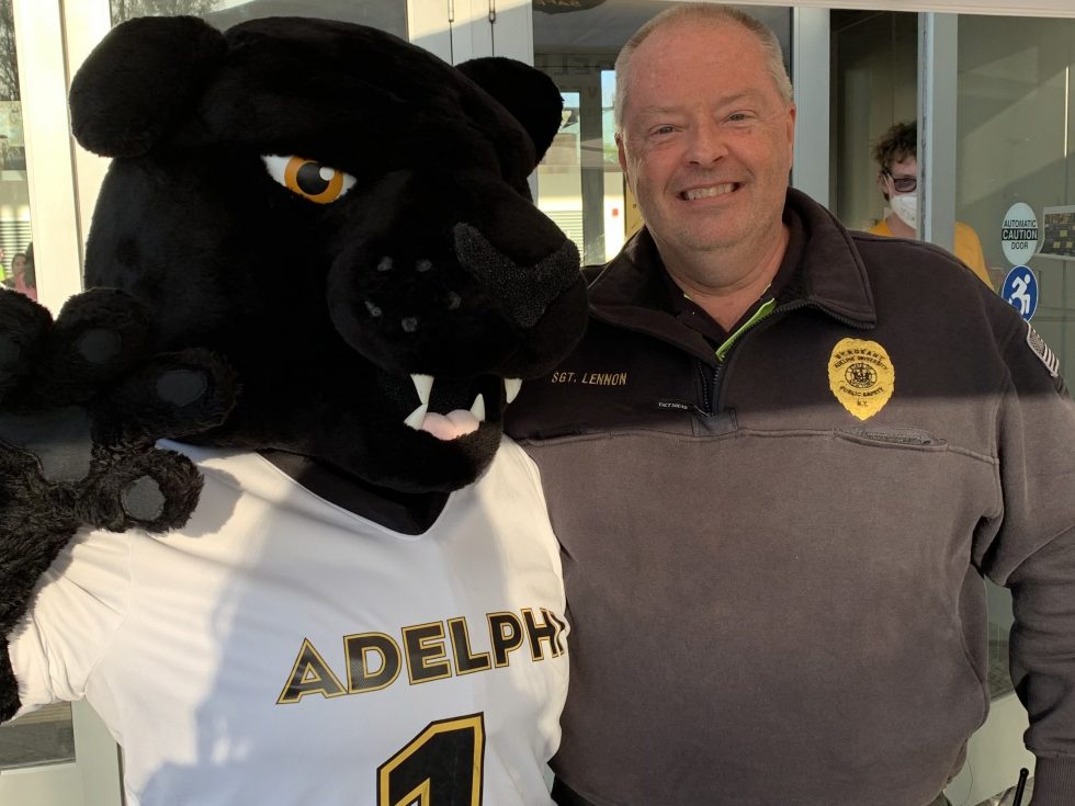 Man wearing dark sweater and panther mascot posing for the camera