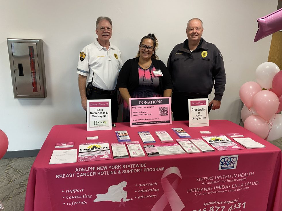 Public Safety smiling behind a Breast Cancer Support Table