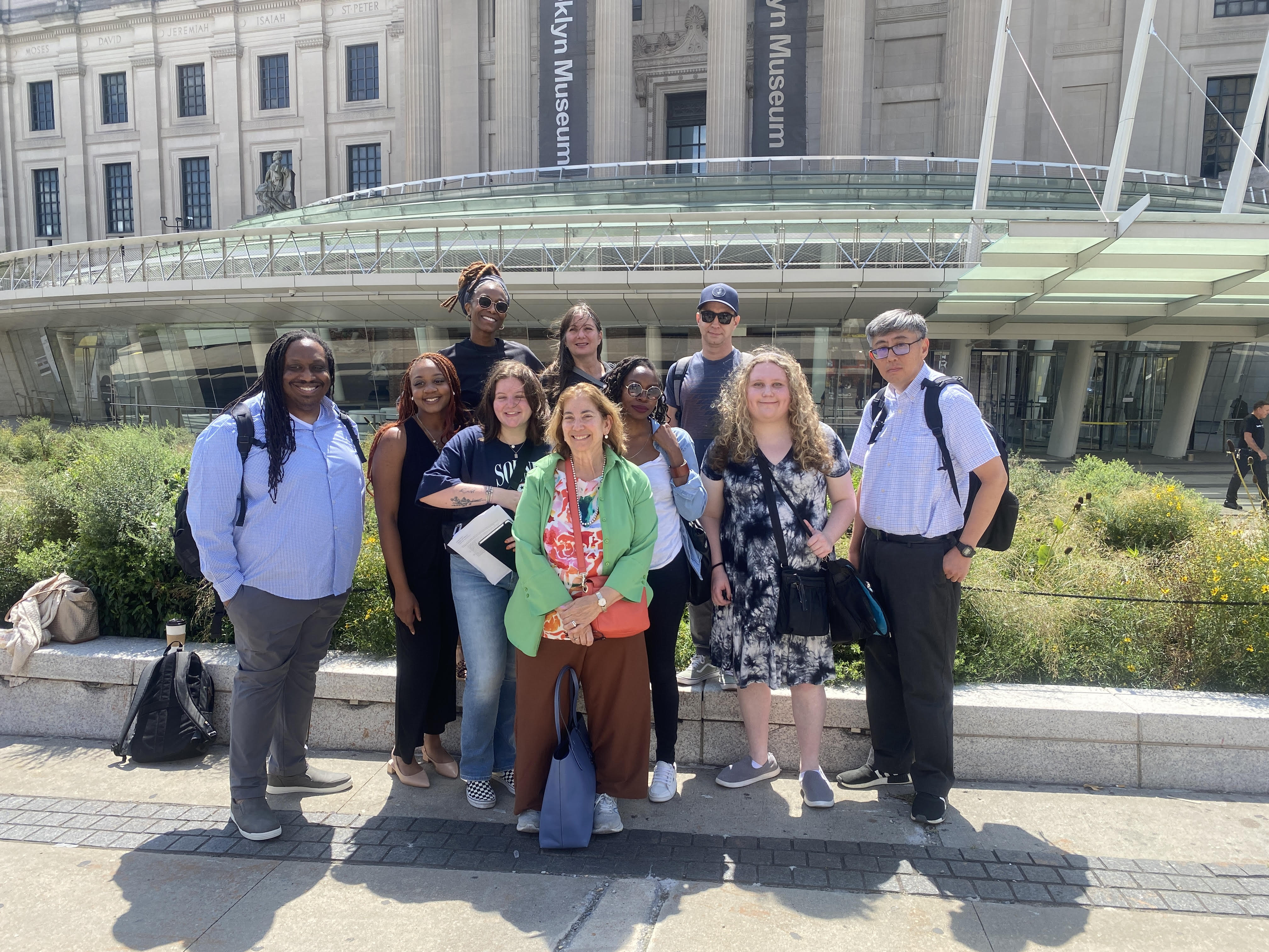 A diverse group of 10 students stands outside the Brooklyn Museum entrance.