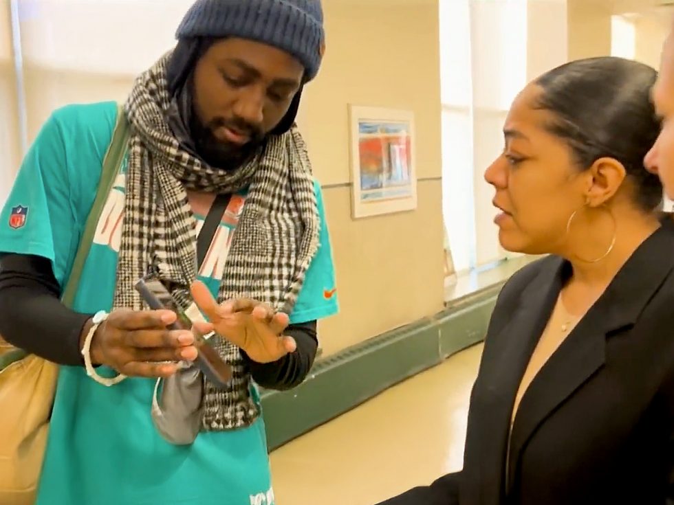 CBS Video Still of Photo Exhibit - Showing an Adelphi University Social Work Student showing professors something on his phone