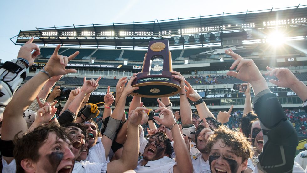 Men’s lacrosse players running across the field in celebration of their win