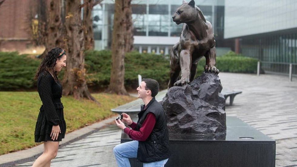 Man and women getting engaged in front of the Adelphi panther statue