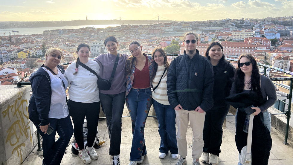 Eight Adelphi students pose above a scenic view of Lisbon, Portugal.